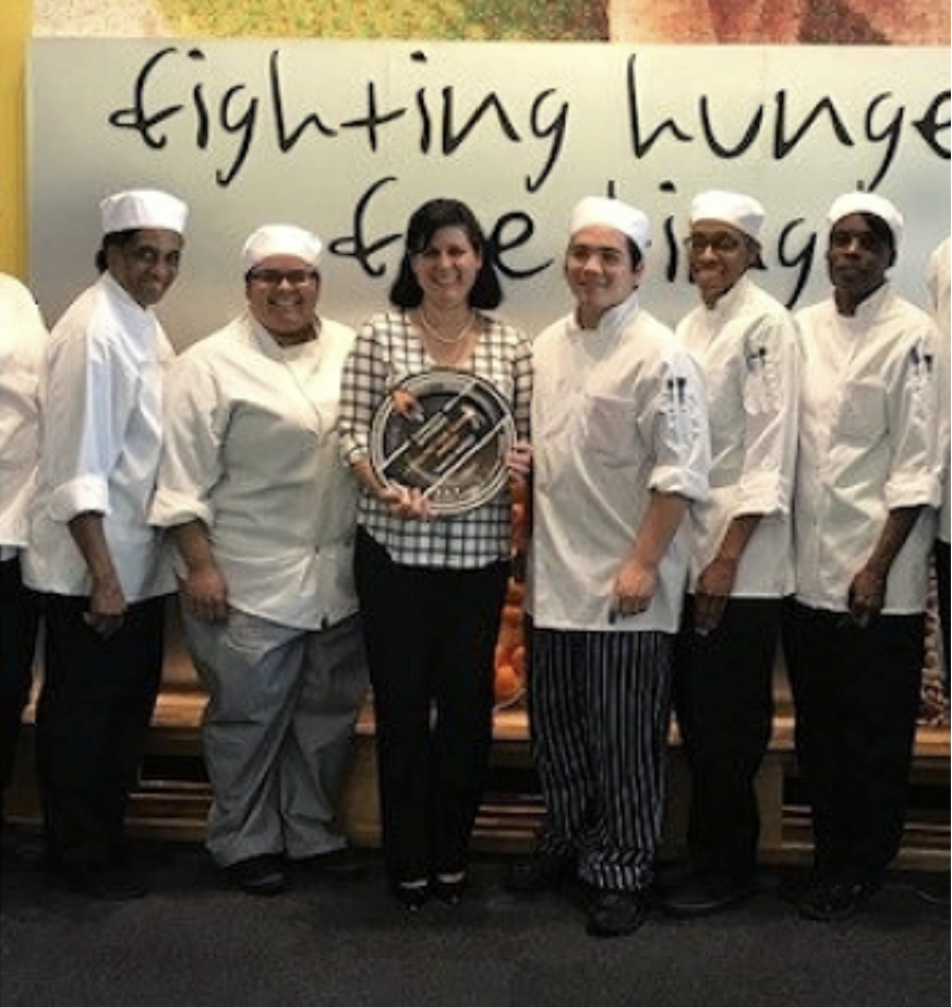 Idalia accepting her award with her students at her side